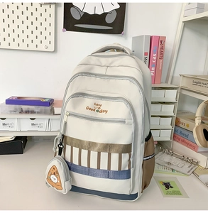 Détail d'un sac à dos scolaire blanc crème avec fermetures et pendentif ours pizza