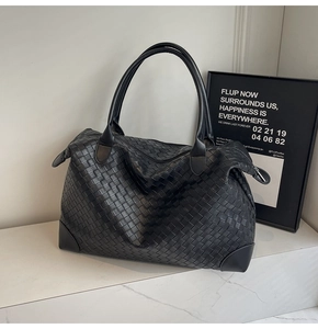 Close-up of black woven tote bag with reinforced leather corners on marble surface