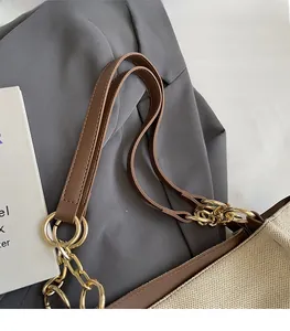 Close-up of beige canvas tote with brown leather straps and gold metal ring hardware