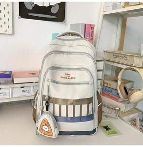 Détail du sac à dos en toile crème avec plusieurs zips et pendentif pizza en peluche