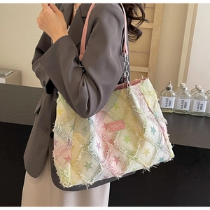 Détail du sac cabas en jean matelassé avec bords effilochés et motifs étoiles