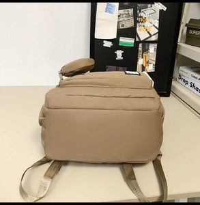 Detail view of khaki nylon backpack with matching mini pouch and brown woven shoulder straps