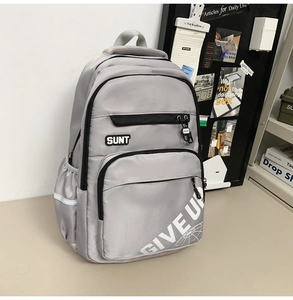 Detail of grey nylon backpack featuring multiple zip layers and decorative printed lettering