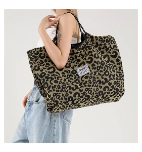 Detailed side view of the large leopard print tote bag with black leather handles