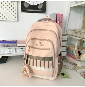 Détail du sac à dos rose pour étudiante avec poches zippées et petit pendentif pizza