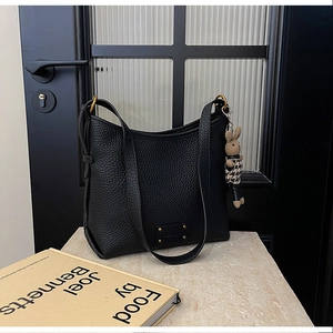 Close-up of black lychee grain leather shoulder bag with a stylish houndstooth bunny charm