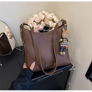 Detail of dark brown leather bucket bag with textured grain and cute bunny charm