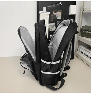 Close-up of black multi-compartment backpack showing durable zippers and side mesh pockets