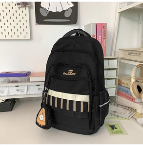 Détail du sac à dos noir avec broderie orange et porte-monnaie en forme de pizza pour fille