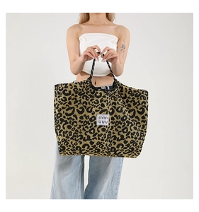 Close-up of leopard print tote bag with white woven label and black top handles