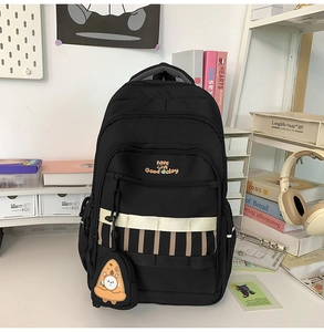 Détail du sac à dos noir avec pendentif pizza et broderie smiley pour écoliers