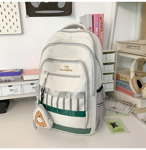 Détail de sac à dos scolaire blanc crème avec compartiments et pochette pizza ronde