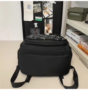 Detailed view of black backpack featuring dual zippers and abstract graphic print detail