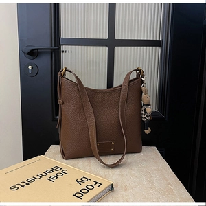 Detail of dark brown pebble leather hobo bag with cute rabbit charm on a stone surface