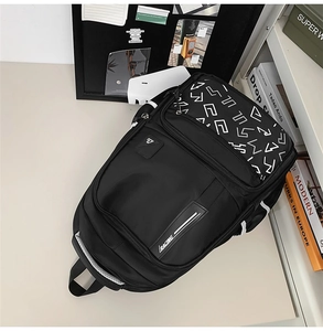 Detail view of durable black backpack showing racing text ribbon and geometric print