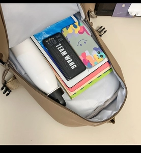 Top view of khaki nylon backpack showing spacious interior with books and electronics