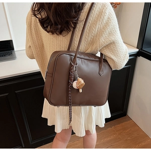 Sac à bandoulière marron en similicuir avec charm de baseball porté par un modèle