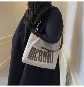 Detail showing high-capacity tote bag with golden chain strap and MCAORI logo print