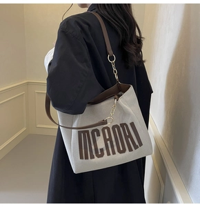 Detail of canvas tote bag showing the leather and gold metal chain shoulder strap