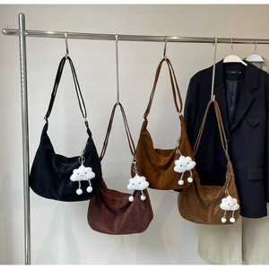 Detail of large suede crescent bags in earth tones with cute white plush charms