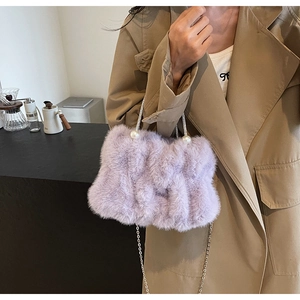 Detail van lavendelkleurige pluche tas met zilveren ketting en grote parelaccenten