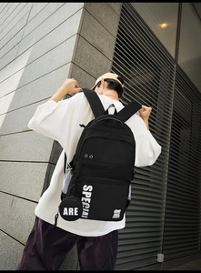 Detailed view of black urban backpack with white SPECIAL logo and side mesh pocket