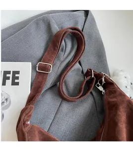 Detail of adjustable long shoulder strap on brown suede tote bag with silver metal buckle