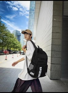 Detail of black backpack side showing white ARE and SPECIAL lettering with mesh pocket
