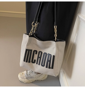 Detail of canvas tote bag with bold MCHORI text and black leather gold chain strap