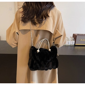 Model draagt zwarte faux fur cloud bag met strass handvat en zilveren kettingriem