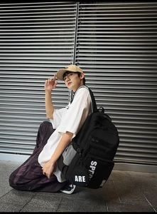 Detail view of black high-capacity nylon backpack featuring sport logo and side pouch