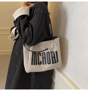 Detail of canvas tote bag featuring leather straps and MCAORI logo on a model