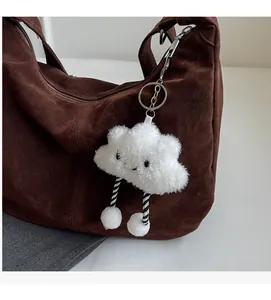 Close-up of a cute white plush cloud charm with striped legs on a brown tote bag
