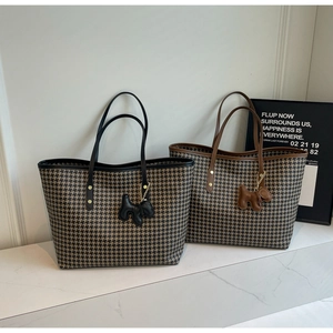 Detail of houndstooth tote bags with leather trim and decorative puppy charms