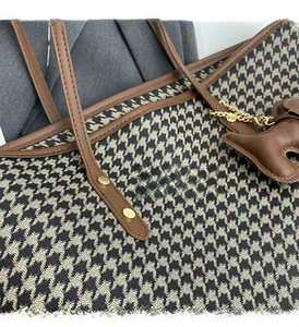 Detail of houndstooth tote bag featuring gold-tone hardware and leather trim