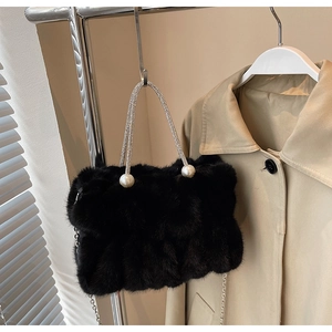 Detail van zwarte pluche handtas met strass handvat en witte parel accenten