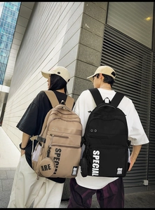 Outdoor shot of stylish large capacity school backpacks in khaki and black with slogans
