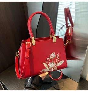 Detailed embroidery of white and gold flowers on premium red crossbody bag with hardware