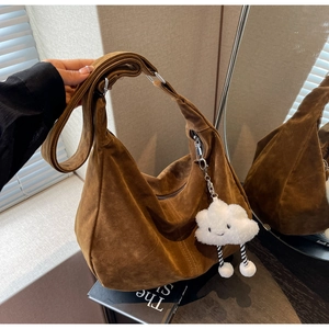 Detail of a large brown suede hobo bag with wide strap and cute plush cloud charm