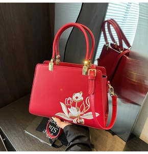 Detailed embroidery of white and gold flowers on a luxury red PU leather handbag with gold metal clasp