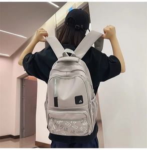 Detail of grey student backpack featuring wide padded straps and racing logo text