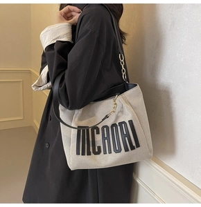 Close-up of canvas tote bag with MICAORL print and leather chain shoulder strap