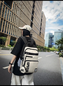 Outdoor street view of a black and white contrast backpack with stylish text patterns