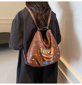 Close-up of brown leather backpack with cartoon burger print and Good Luck text