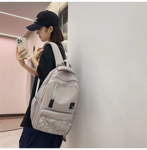 Side view of light grey minimalist backpack with multi-pocket design on model