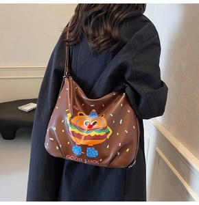 Detail of a large brown leather tote bag with a cute burger cartoon and slogans