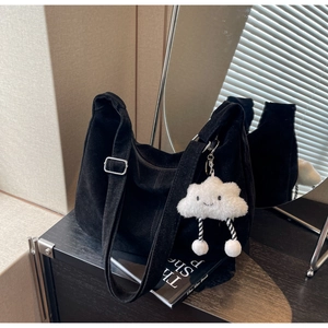 Detail of black corduroy tote bag showing adjustable strap and plush cloud charm