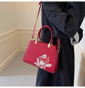 Detailed embroidery of white tulips on a red luxury leather crossbody handbag
