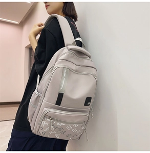 Close-up of lightweight nylon travel backpack showing multi-pocket design and racing label