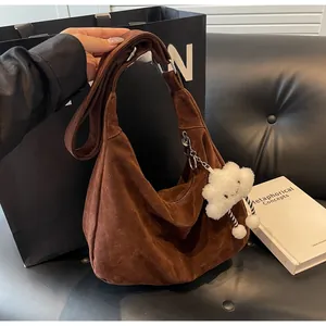 Detail of brown suede hobo tote with wide strap and a plush white cloud pendant